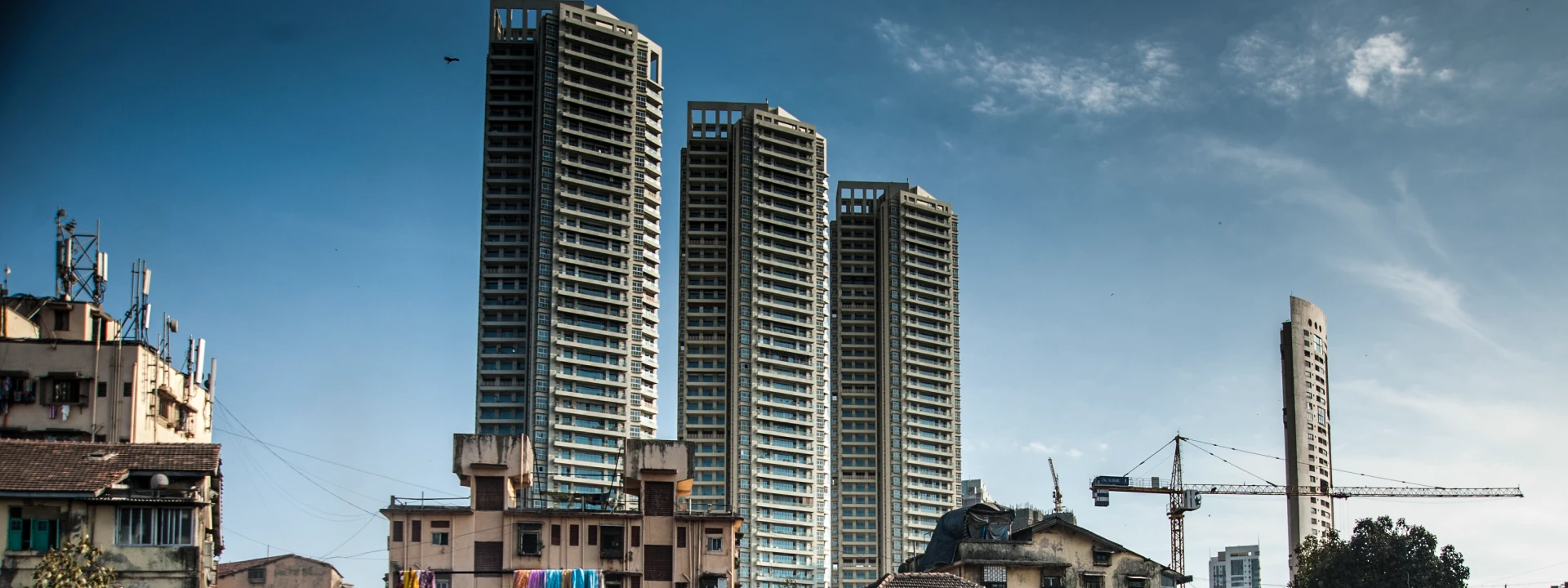 Tall residential buildings rising next to older structures in a city.
